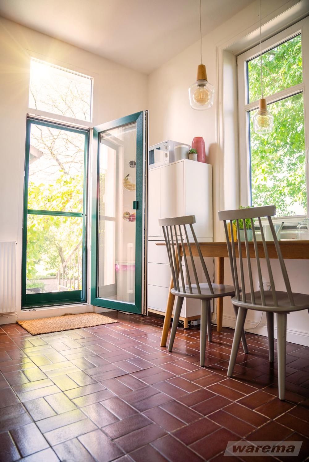 Holztreppe neben großem Fenster mit geöffnetem Raffstore, Blick auf Garten mit Pflanzen